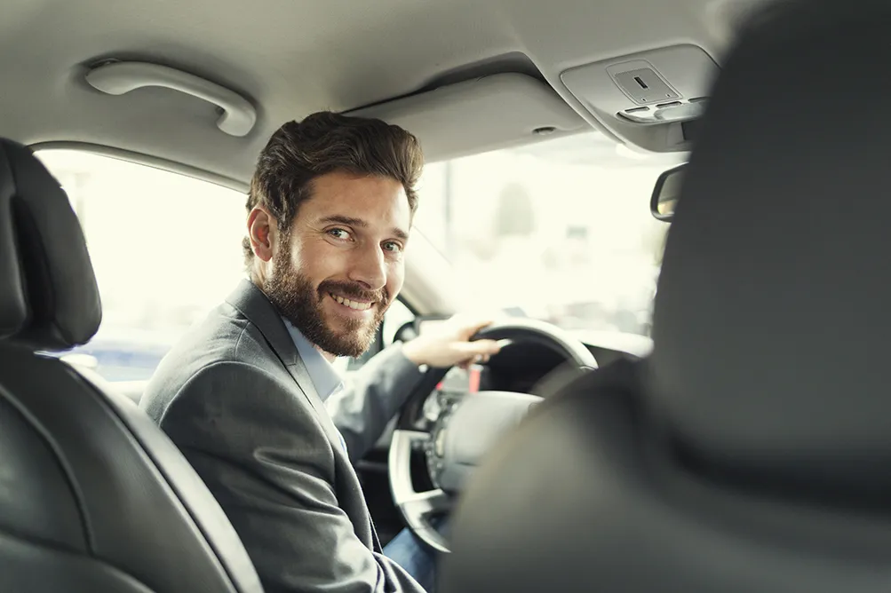 Fahrschule Two for You GmbH – Porträt eines Mannes in seinem Auto. Blick in die Kamera